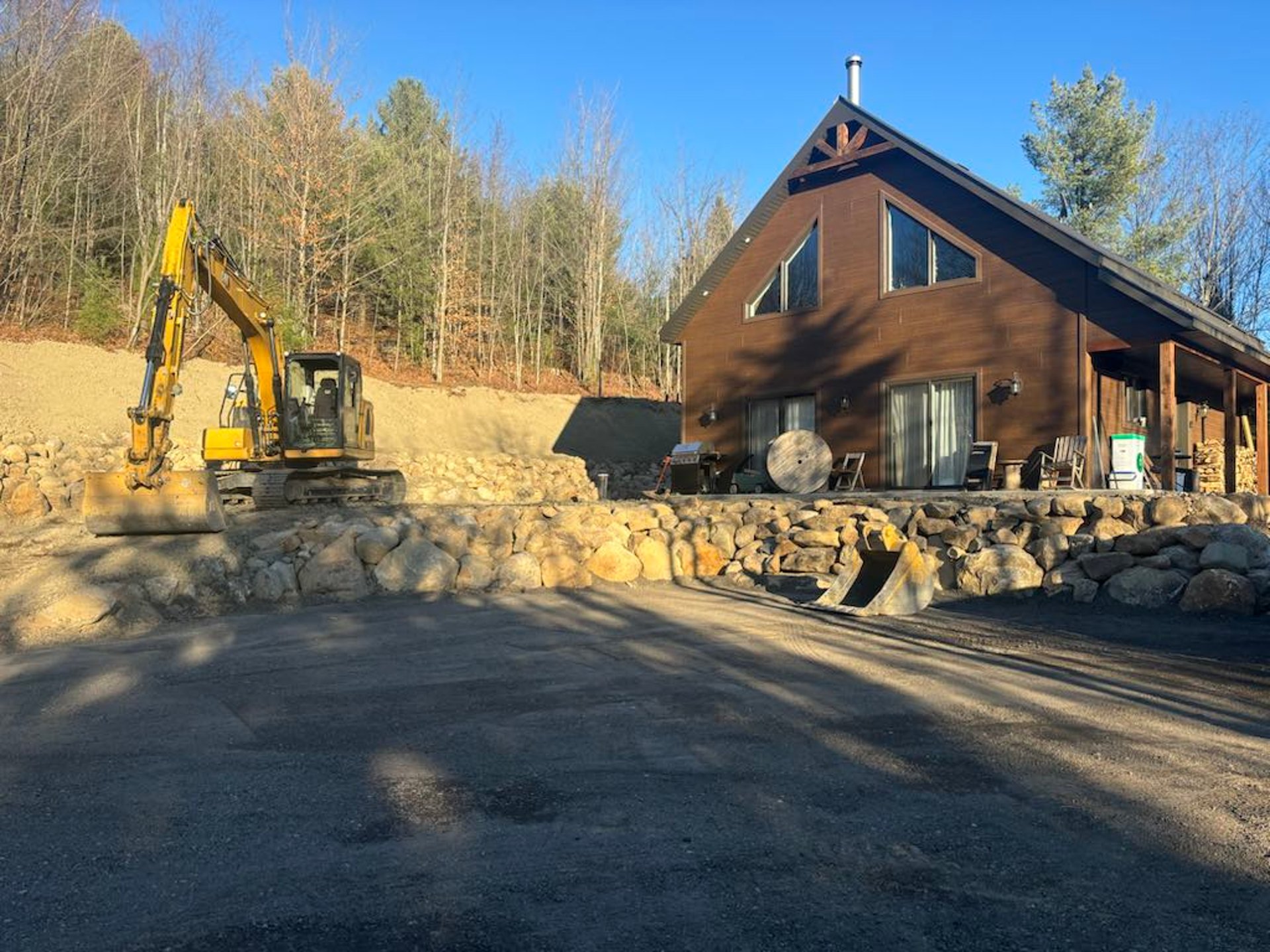 Pelle mécanique devant un chalet après des travaux de terrassement
